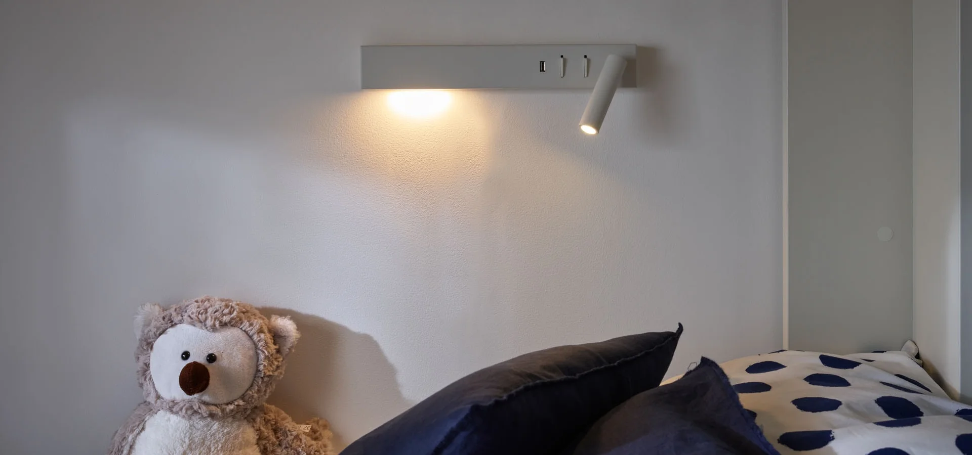 Lampka na ścianie zawieszona przy łóżku piętrowym 